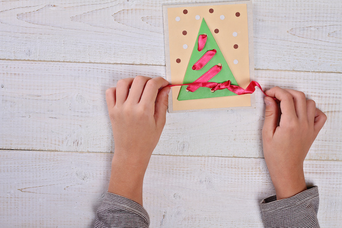 Close up on child's  hands making Christmas Tree from colored paper.   Kids Art, Art Projects, Handmade New Year decorations